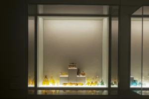 Veduta di una delle vetrine della sala vetri con balsamari e contenitori in vetro soffiato giallo.